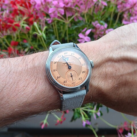 A jump hour watch on a hairy wrist. Floral background. 